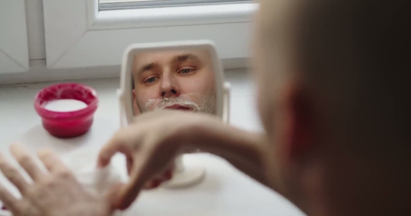 A man applying face cream in a mirror