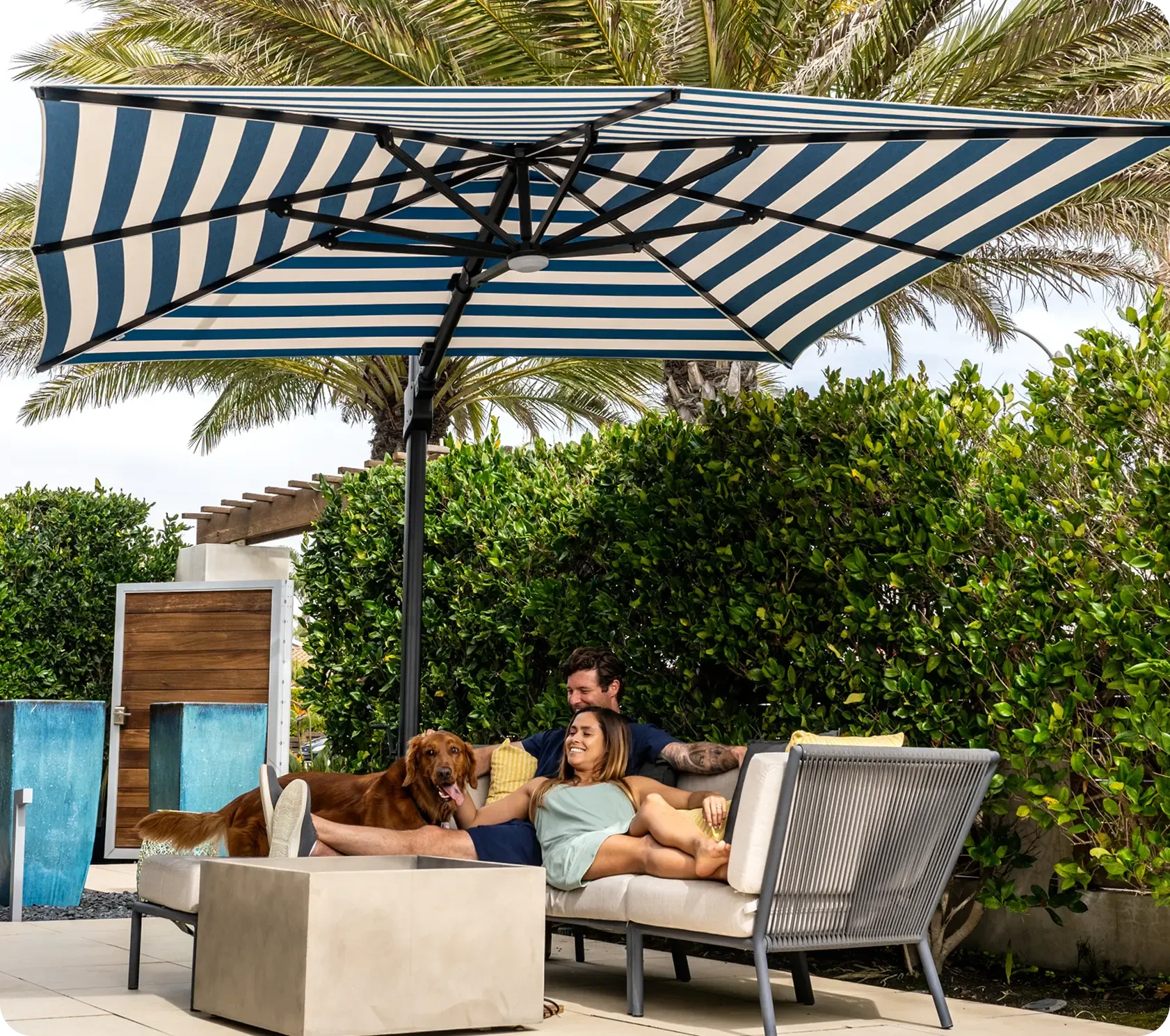 Midtown Umbrellas: a striped umbrella shading a couple and their dog on a patio
