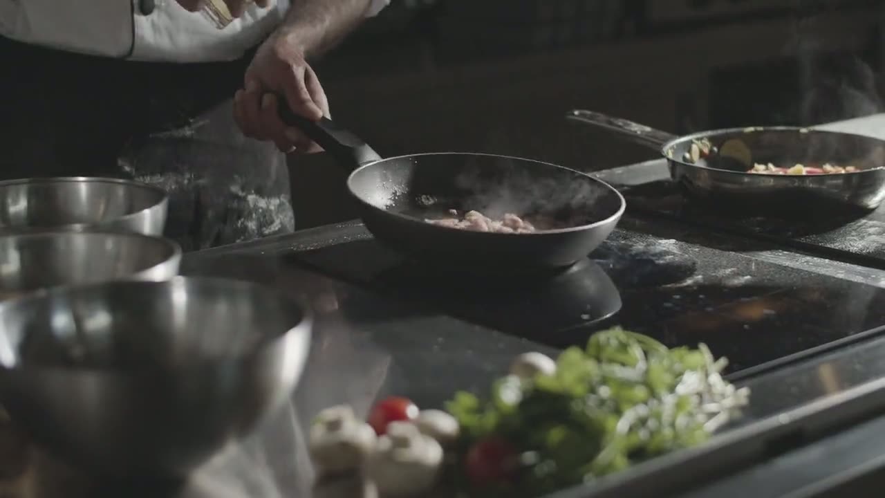 A chef cooking over a smoking pan